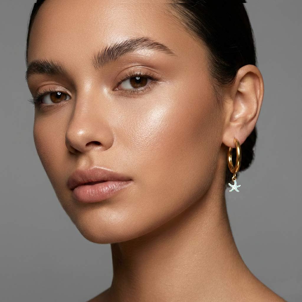 Pendiente aro de acero dorado con estrella de mar blanca con pintitas turquesas puesto en modelo. Pendientes de acero inoxidable Algo de Olga.