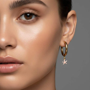 Pendiente aro de acero dorado con estrella de mar rosa esmaltada puesto en modelo. Pendientes de acero inoxidable Algo de Olga.