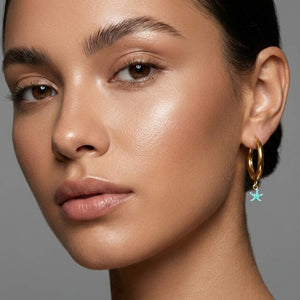 Pendiente aro de acero dorado con estrella de mar turquesa con pintitas blancas puesto en modelo. Pendientes de acero inoxidable Algo de Olga.