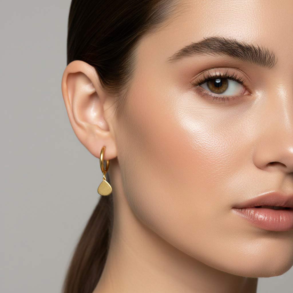 Mujer con pendientes de aro dorados minimalistas con charm de gota — pendientes ligeros para pelo recogido, oficina o regalo, en acero hipoalergénico