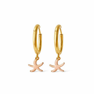 Aros de acero dorado con colgante de estrella de mar esmaltada en rosa con pintitas blancas sobre fondo blanco. Pendientes de acero Algo de Olga.