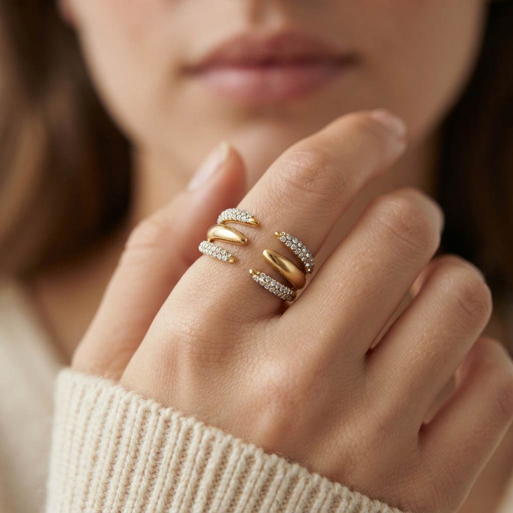 Mano con anillo Jenner de acero dorado abierto con cristales blancos y jersey crudo