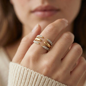 Mano con anillo Jenner de acero dorado abierto con cristales blancos y jersey crudo