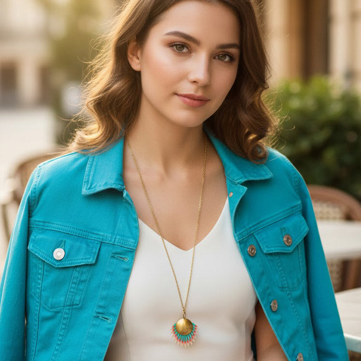 Modelo con collar artesanal Amazonia Multicolor de piel pintada a mano y medallón dorado con chaqueta turquesa en exterior. Joyería artesanal Algo de Olga.