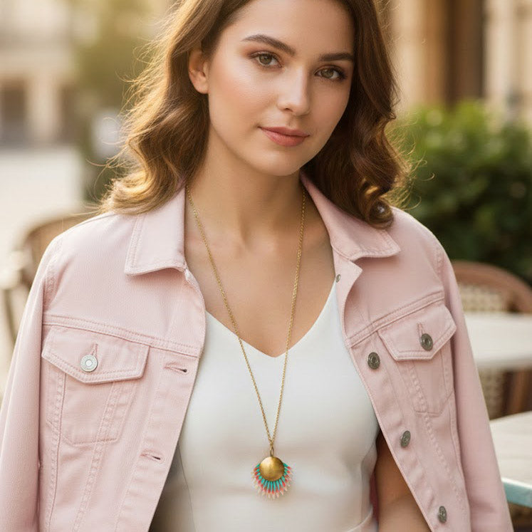 Modelo con collar artesanal Amazonia Multicolor hecho a mano con medallón de latón dorado y piel pintada en coral y turquesa con chaqueta rosa. Algo de Olga.