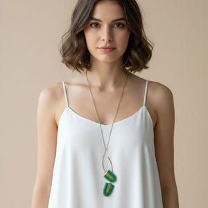 Collar largo artesanal Verde Tropical Doble con dos colgantes de piel pintada en verde esmeralda y latón satinado sobre cadena dorada regulable.