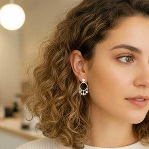 Pendientes de presión con tornillo con un aro donde le cuelgan plaquitas y estrellas. Es un pendiente de plata con baño en rodio. Tiene un tamaño mediado - Algo de Olga. En esta foto lo lleva puesto una modelo.