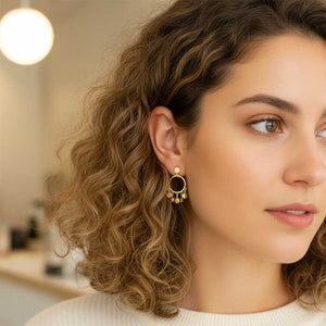 Pendientes de presión con tornillo con un aro donde le cuelgan plaquitas y estrellas. Es un pendiente de plata con baño en oro de 18kts. Tiene un tamaño mediado - Algo de Olga. En esta foto lo lleva puesto una modelo.