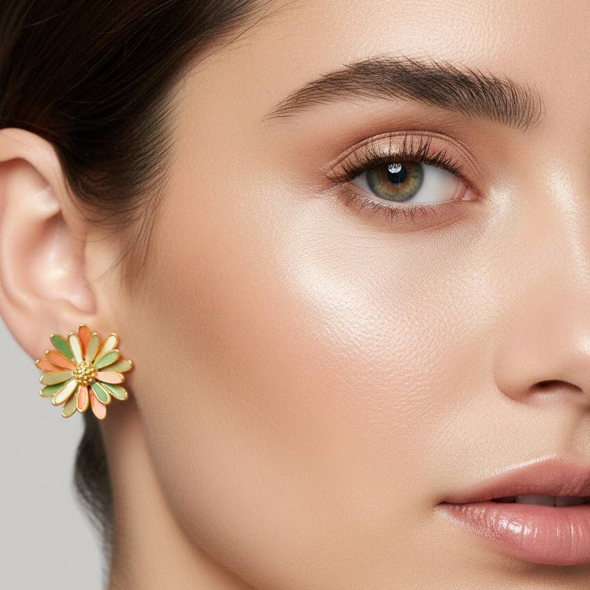 pendiente de botón en forma de margarita esmaltada en tonos coral, naranja, verde y crema con centro dorado puesto en modelo. Pendientes Inés Flor Algo de Olga.