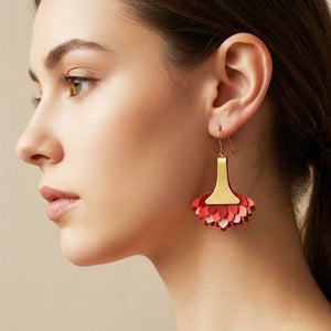 La modelo lleva puestos unos pendientes artesanales llamados Paraíso en color rojo que son de piel pintada en degradado coral y burdeos con base de latón satinado, hechos a mano.