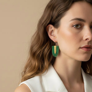 La modelo lleva puesto los pendientes artesanales Verde Tropical de piel pintada a mano con forma tropical y base de latón satinado, hechos a mano.