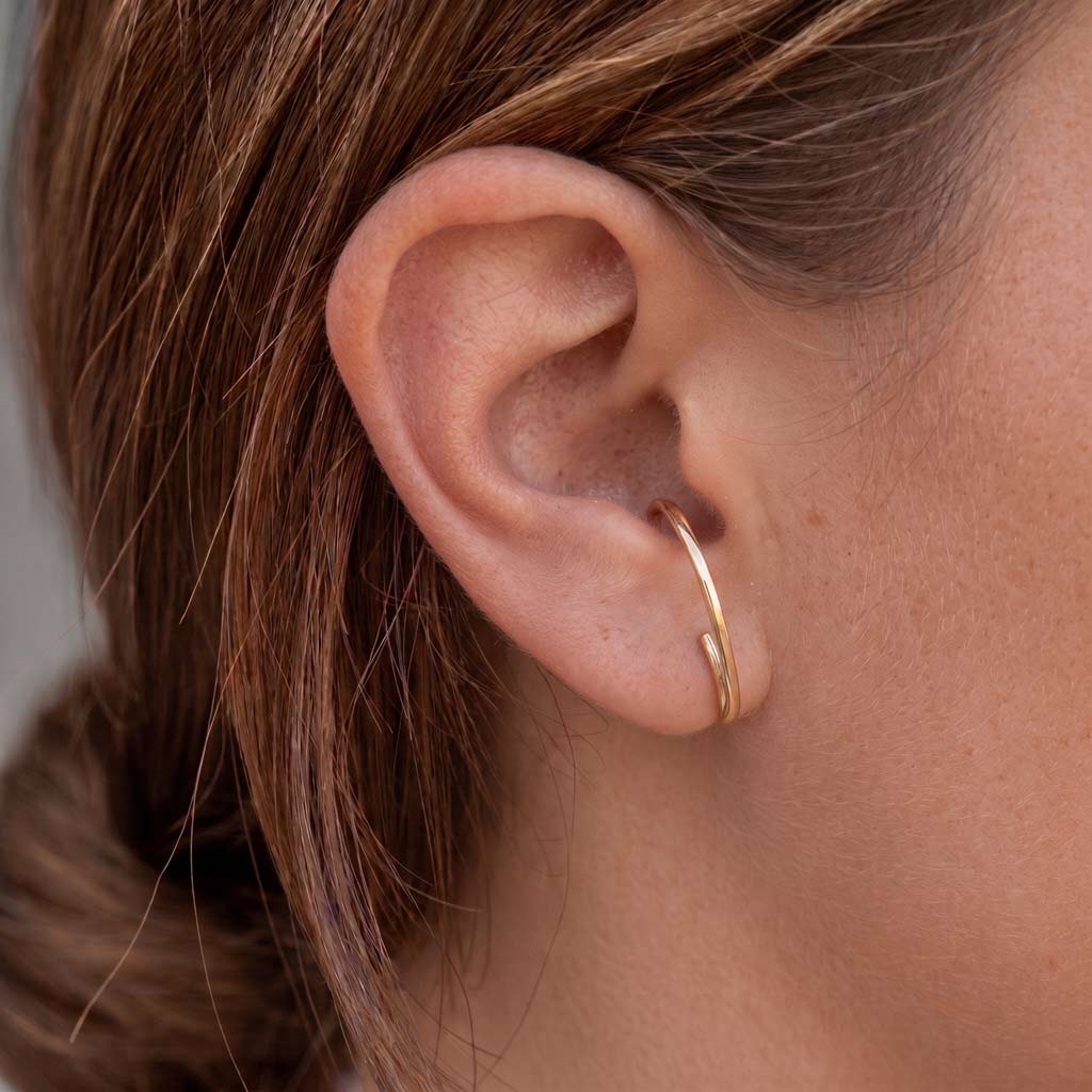 Modelo con pendiente semiaro Nikki dorado que se sujeta al hueco de la oreja