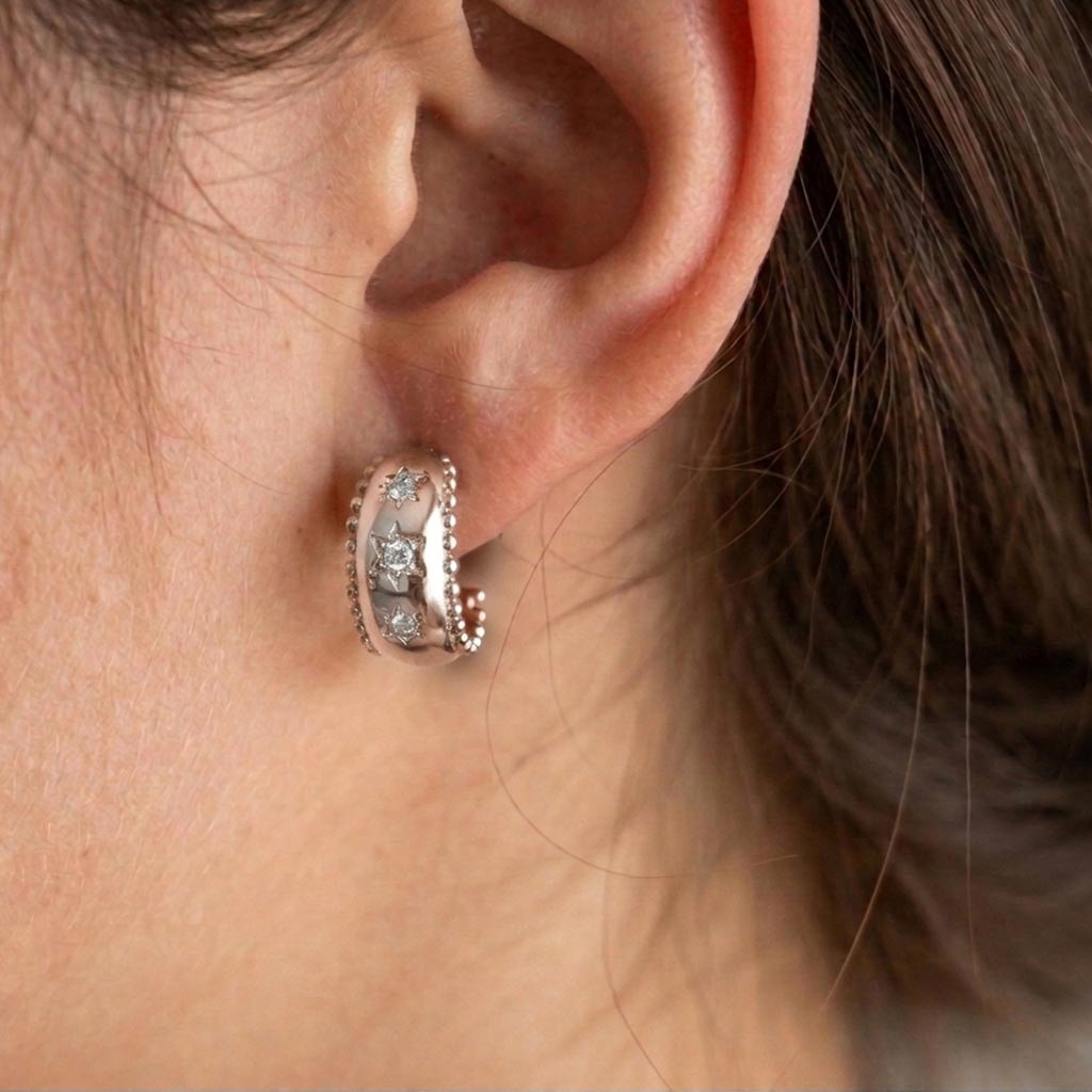 pendiente semiaro Nieves de plata rodiada con estrellas en relieve y circonitas blancas puestos en una modelo