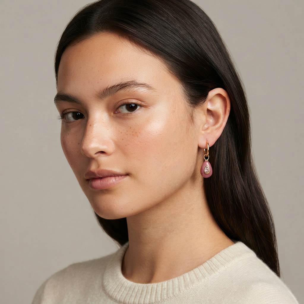 Modelo con pelo suelto y pendiente de aro Aoki dorado con rodonita rosa y circonita