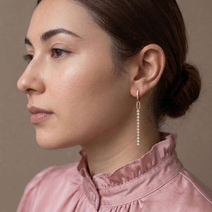 Modelo con moño y pendiente de aro Erin dorado con hilera de circonitas blancas