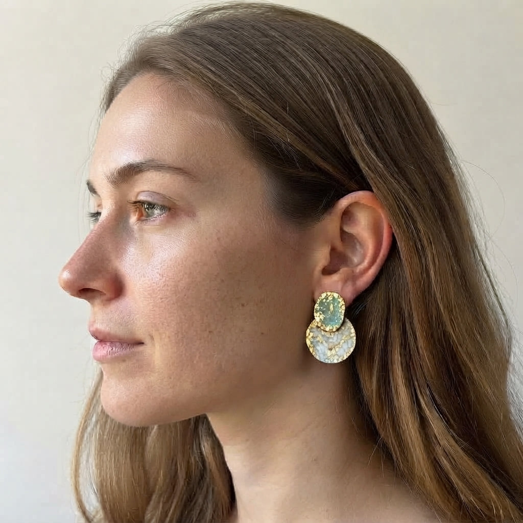 Pendientes de acero dorado martillado con esmalte verde azulado. De tamaño mediano, originales y fáciles de combinar puestos en una modelo.