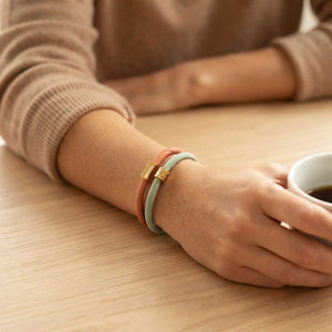 Pulsera de seda color coral con tubo desigual de acero dorado y alargador puesta en una modelo
