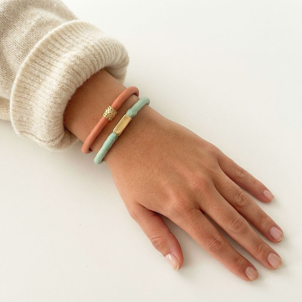 Pulsera de seda verde menta con tubo desigual de acero dorado y alargador puesta en una modelo.