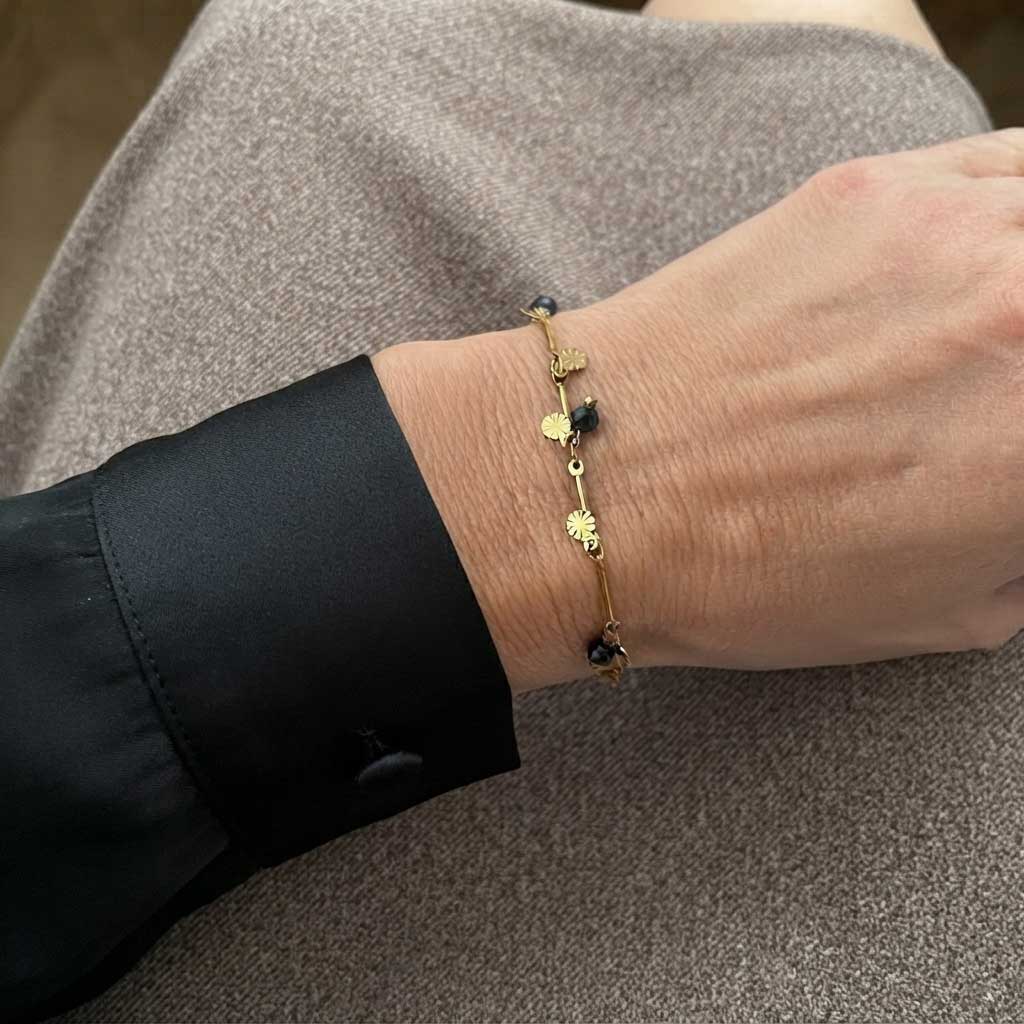 Pulsera Viviana dorada con cuentas de ónix negro y puño de camisa negra puesta en una modelo